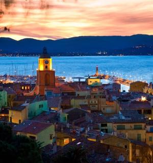 a city with a clock tower and the ocean at night