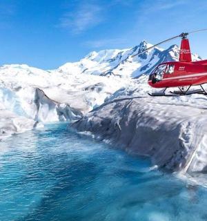 a red helicopter is flying over a river