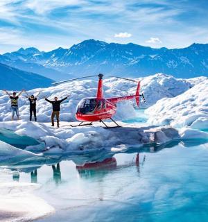 three people are standing next to a helicopter in the snow