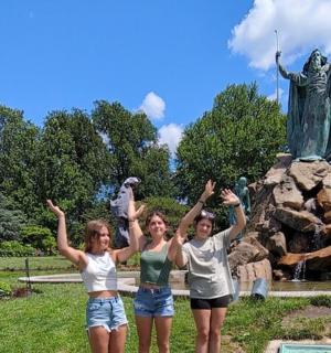 tři dívky stojí před sochou