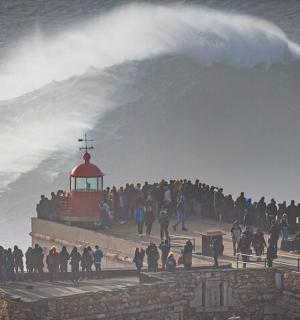 一群人站在码头上,看着海浪