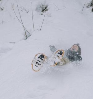 一名男子躺在雪地里，带着滑雪板