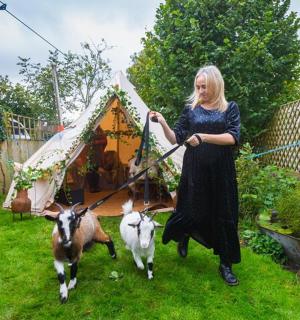 eine Frau mit zwei Ziegen in einem Hof