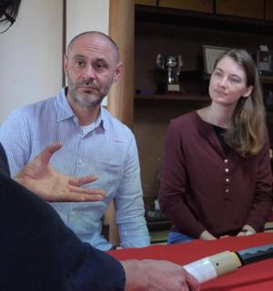 two men and a woman standing next to a table