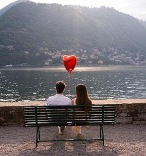 muž a žena sedící na lavičce s balónkem ve tvaru srdce