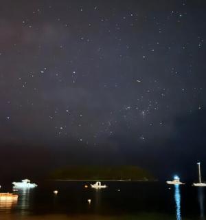 hvězdná obloha s loděmi ve vodě v noci