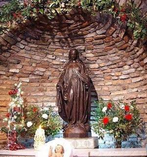 a statue in front of a brick wall with flowers