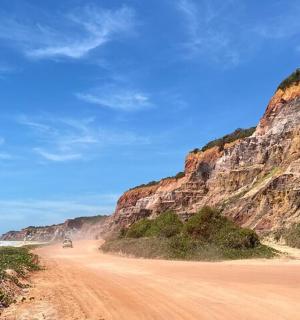 eine unbefestigte Straße neben einem felsigen Strand mit dem Meer