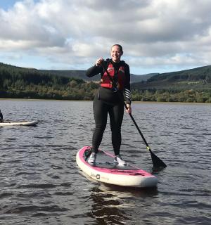 一名男子站在水中的桨板上