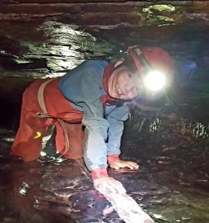 一名男子拿着手电筒穿过一个洞穴