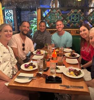 skupina lidí sedících kolem stolu s jídlem