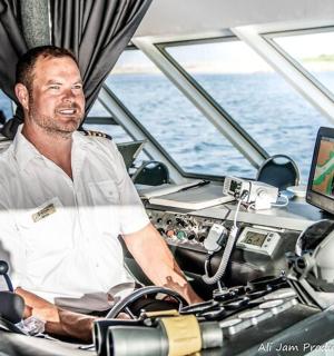 ชายคนหนึ่งนั่งอยู่ที่หางเสือเรือ