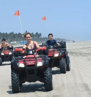 three people riding atvs on the beach