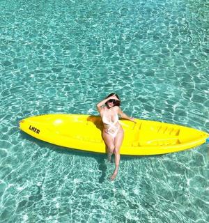 a man standing next to a yellow kayak in the water