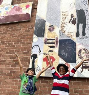 两个孩子站在壁画墙前