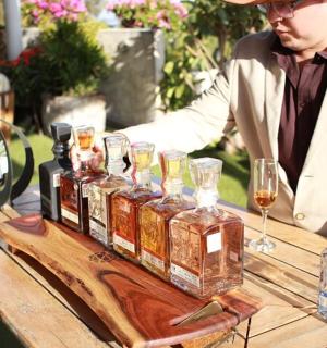 a man sitting at a table with several bottles of alcohol
