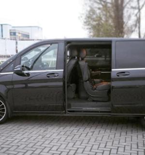 a black van with its door open sitting on a brick road