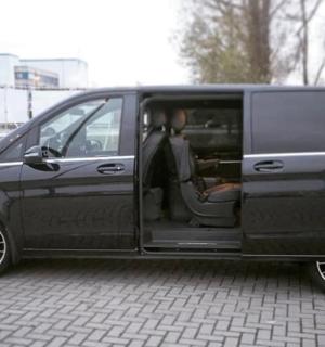 a black van with its door open sitting on a brick road