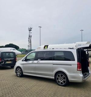 a white van with its door open next to an airplane