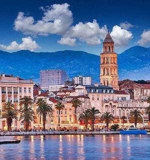 uma cidade com uma torre de relógio, palmeiras e água