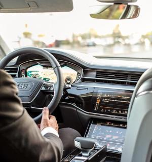 muž řídící auto s počítačem na volantu