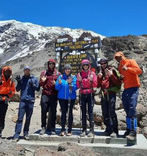 一群人站在山上的一块标志牌前