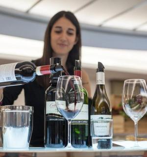 a woman pouring wine into two wine glasses