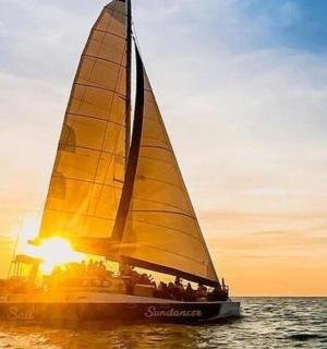a sailboat in the ocean with the sun setting