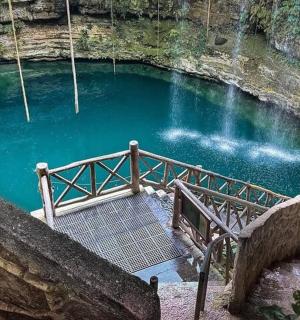 a pool of blue water with a staircase in a cave