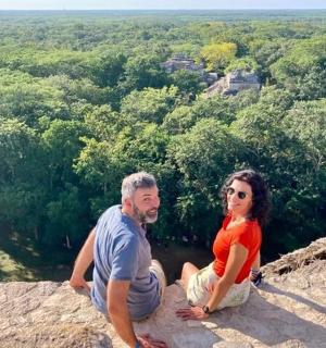 a man and a woman sitting on top of a rock