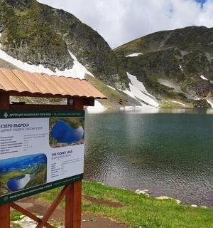 uma placa interpretativa em frente a um lago de montanha