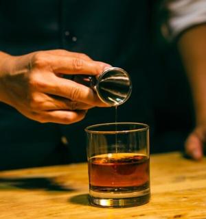 一个人把饮料倒进玻璃杯