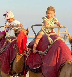 两个孩子在海滩上骑着骆驼