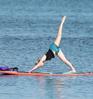 一个人在水中的冲浪板上做倒立