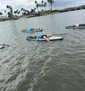 一群人躺在水中的冲浪板上