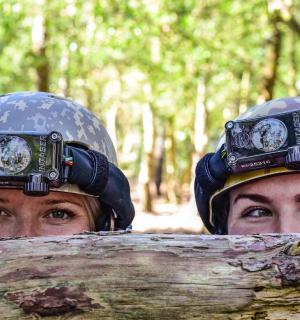 two people with helmets on their heads and a log
