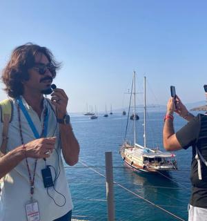 two men standing near the water taking a picture of a boat