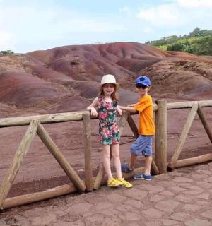 a boy and a girl standing next to a wooden fence