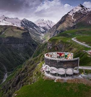 a building on a hill with mountains in the background