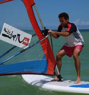 en mand på et surfbræt med et sejl på havet