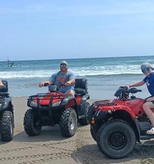 a group of people riding atvs on the beach