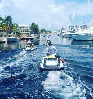 dva lidé jedoucí na koloběžkách v řece s loděmi