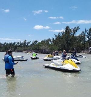 skupina lidí stojících ve vodě vedle lodí