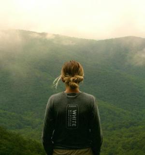 a woman standing on top of a mountain looking at the mountains