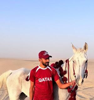 muž stojící vedle bílého koně v poušti