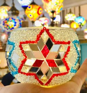 a hand holding a glass bowl with a mosaic design on it