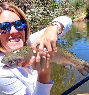 žena držící pstruha potočního ve vodě