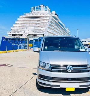 a van parked in a parking lot next to a cruise ship