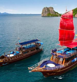two boats with a red sail in the water
