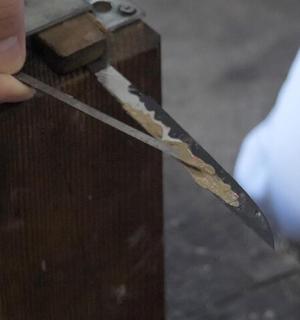 a person holding a knife on a piece of wood